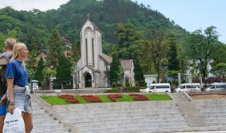 Family exploring Sapa town square with the Stone Church and green mountains