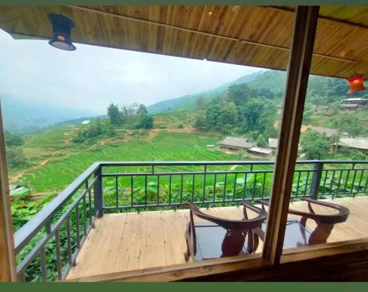 Wooden balcony with two chairs overlooking green terraces and houses