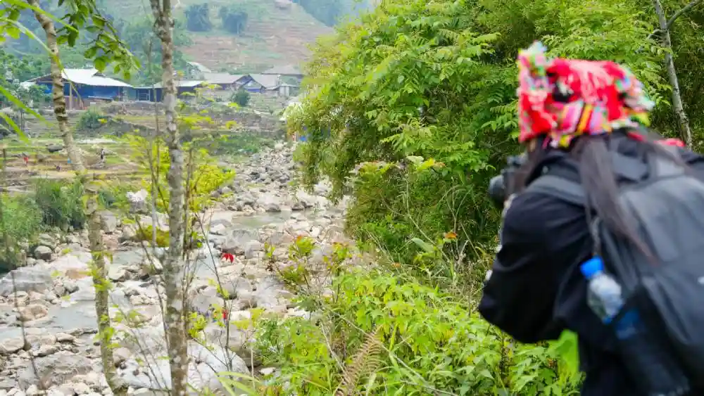 Red Dao woman trekking along a stream towards a remote Sa Pa village on the Off-the-Beaten-Path Trek