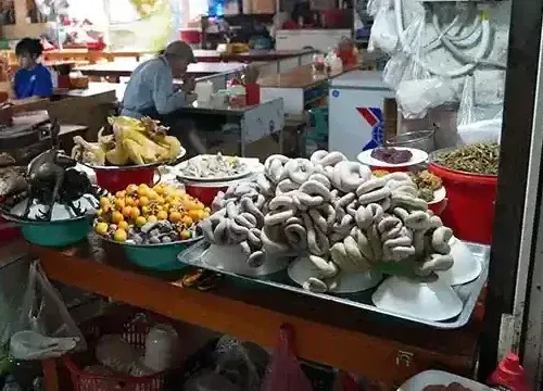 Sapa Food Market stalls displaying smoked buffalo meat, free-range chicken, mountain herbs and seasonal produce inside the local three-story market hall