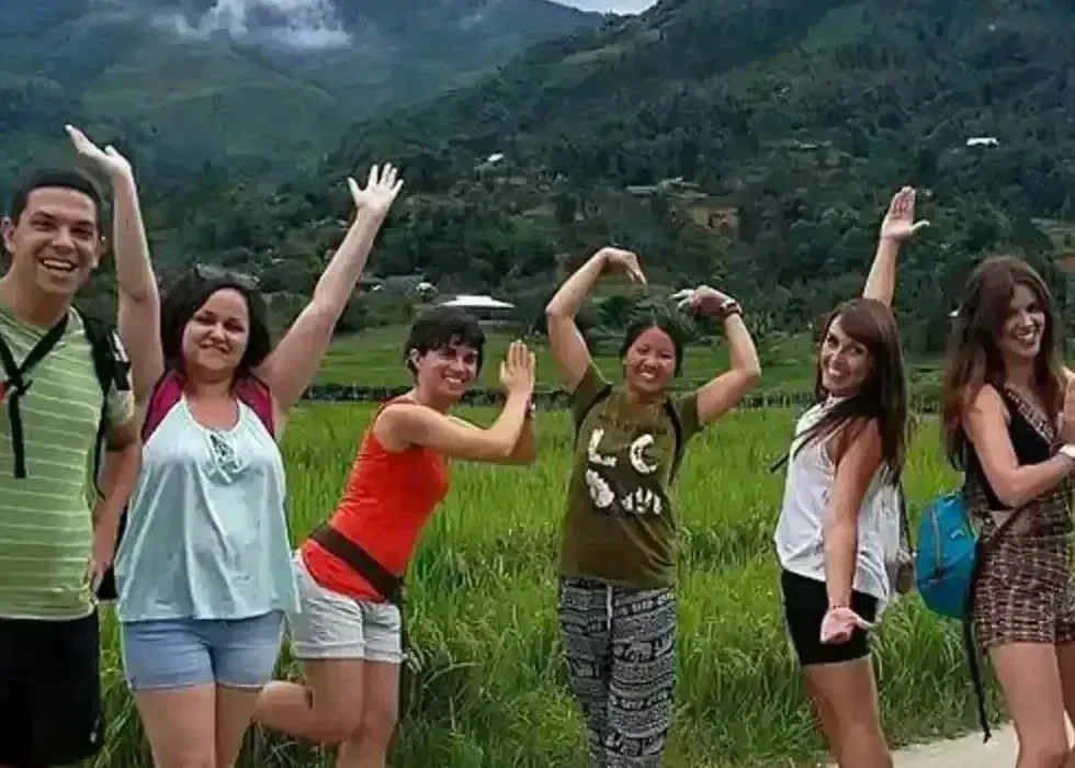 Group of travelers smiling with local Hmong guide in Sapa rice fields