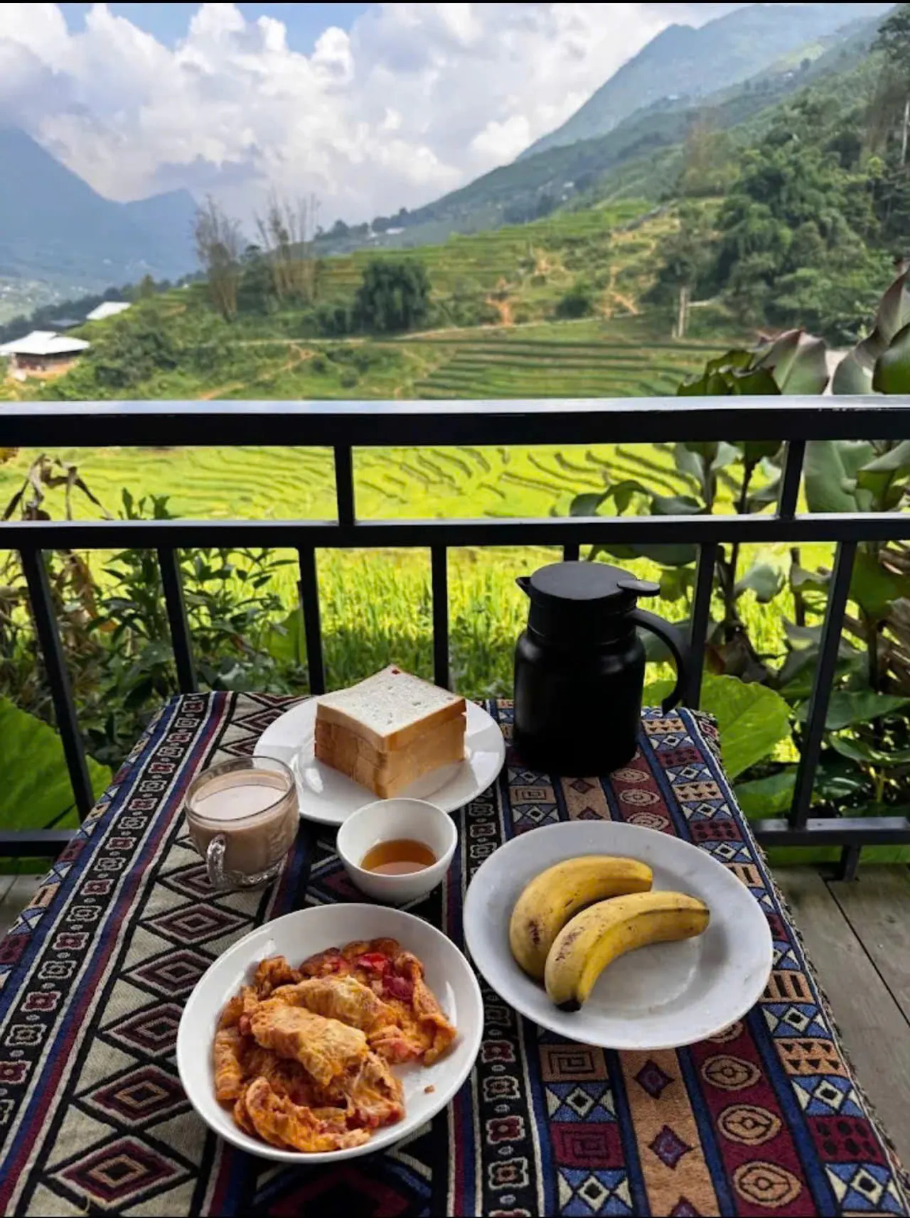 Breakfast on a balcony table with rice terraces beyond the rail.
